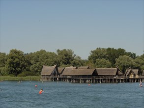 A historic pile-dwelling village on a calm lake with several buoys, Meersburg, Lake Constance,