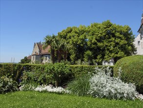 Castle in the background of a well-tended garden with trees, palm trees and colourful flowers on a