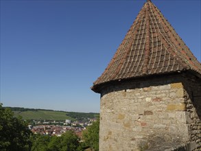 Historic stone tower and wall with a view of the village and surrounding vineyards in the sunshine,