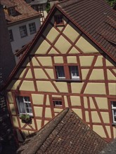 A half-timbered house with red roofs and several windows, under a blue sky in the shade, Meersburg,