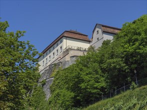 Large castle on a hill surrounded by dense green trees and sunny skies, Meersburg, Lake Constance,