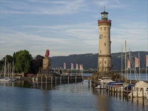 Lighthouse on the water with boats and flags in an evening atmosphere, Meersburg, Lake Constance,