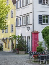 Colourful house facades with windows, trees and a cosy street café in a historic old town,