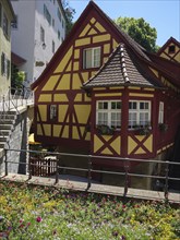 Charming half-timbered house with blooming flowers in front of it in an old town under bright