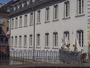 An urban sight with white buildings, lots of windows, parasols and a low barrier, Saarburg,