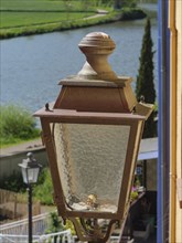 Close-up of an old street lamp next to a river, surrounded by nature, Saarburg, germany