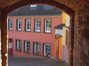 View through an archway of colourful houses in an old town with flower pots on the windowsills and