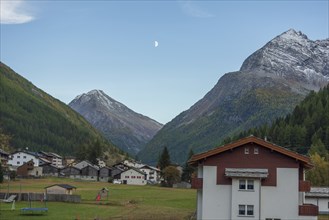 A mountain village with scattered houses in a valley between high mountains under a clear sky with