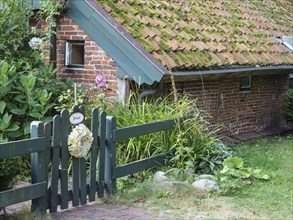 A small brick house with a moss-covered roof and a garden fence, Spiekeroog, East Frisia, GERMANY