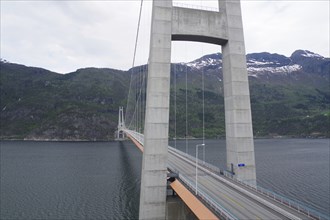 Large bridge over a fjord with mountains in the background under a cloudy sky, Hardanger,