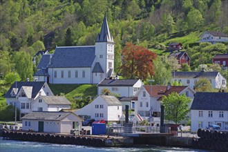 Village with church on a green hill, surrounded by wooden houses and a ferry pier, Utne, Hardanger,