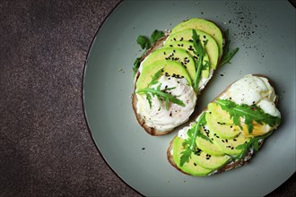 Sandwich with cream cheese, sliced avocado and boiled egg, arugula, on grainy bread, homemade,