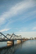 A calm river flows under a the famous old bridge in Kampot town in Cambodia, reflecting the clear