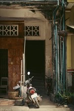 An old, weathered building entrance with a motorbike parked in front exuding a rustic and urban