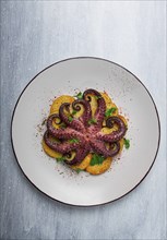 Octopus with potatoes and spices, on a light plate, top view, no people, homemade, close-up