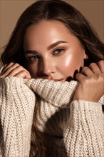 Beautiful young girl with gentle make-up in warm sweater and long straight hair. Beauty face.