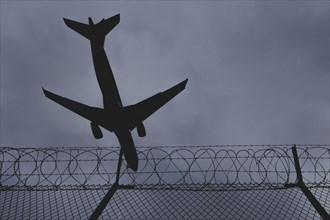 An aircraft looms over a barbed wire fence, taken at Berlin Brandenburg Airport 'Willy Brandt'Äô