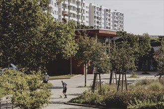 A boy with a football stands out in a green area between blocks of flats in Marzahn, taken in