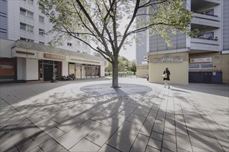A woman walks next to a tree along a prefabricated building, taken in Berlin, 07/08/2024