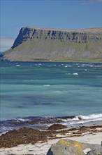 A rocky coastline with sharp-edged cliffs jutting out into the blue sea, Latrabjarg, Vestfirdir