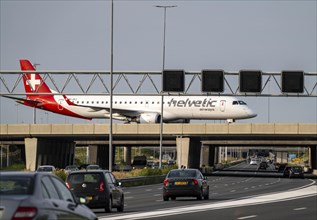 Amsterdam Schiphol Airport, Helvetic Airways Embraer ERJ-195, aircraft on the taxiway, bridge over