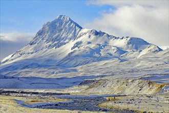 Imposing snow-covered mountain under a slightly cloudy blue sky, winter, Öxnadalur, Akureyri,