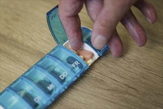 An elderly man takes pills from a pill box. Berlin, 05.08.2024