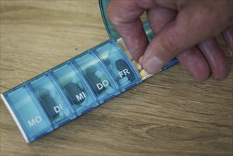 An elderly man takes pills from a pill box. Berlin, 05.08.2024