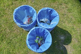 Rubbish bins with blue bin liners standing in a meadow, top view, Germany, Europe