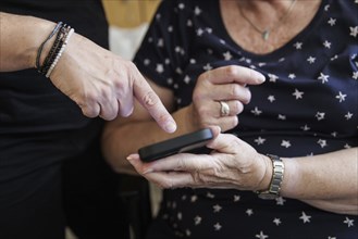 A daughter explains how to use a smartphone to her mum. Berlin, 05.08.2024