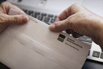 An elderly woman opens a letter from Deutsche Rentenversicherung. Berlin, 05.08.2024