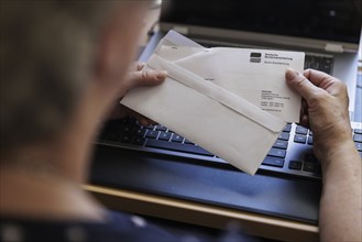 An elderly woman opens a letter from Deutsche Rentenversicherung. Berlin, 05.08.2024