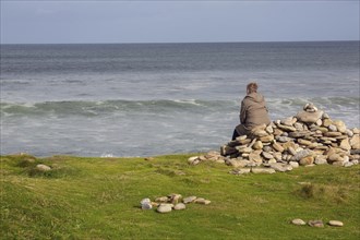 A woman looks out to sea on a stormy day along the Wild Atlantic Way Strandhill, Sligo, Ireland,