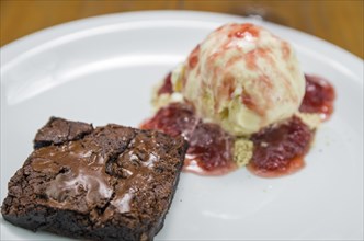 Close-up of delicious chocolade brownie dessert with cream ice cream and raspberry beer