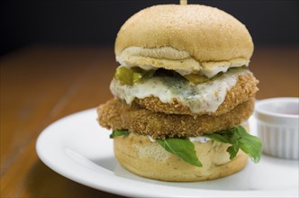 Close-up of homemade tasty chicken burger on wooden table and black background