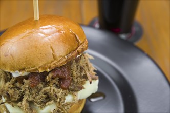 Close-up of tasty homemade pulled pork burger on wooden table and black background