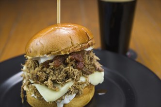 Close-up of tasty homemade pulled pork burger on wooden table and black background