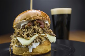 Close-up of tasty homemade pulled pork burger on wooden table and black background