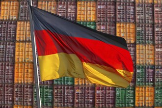 Symbolic image of the German economy: German flag in front of a large stack of shipping containers