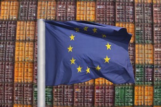 Symbolic image of the economy in the EU: EU flag in front of a large stack of shipping containers