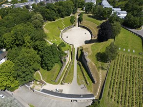 Aerial view of an ancient amphitheatre, surrounded by dense greenery and park-like surroundings,