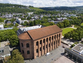 Ancient Roman building made of brick, seen from above, surrounded by city elements and green trees