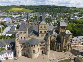 Historic cathedral with towers, surrounded by cityscape and hills under blue sky in Trier, aerial