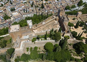 Aerial view of a castle with surrounding walls and buildings, embedded in a green environment with