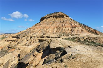 A single hill rises in a barren desert landscape under a clear blue sky, Bardenas Reales Natural