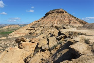 Stony hill in a desert-like landscape under a blue sky with few clouds, Bardenas Reales Natural