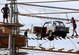 Berlin, 31.07.2010, Climbers balance over a Trabant suspended on ropes in the high ropes course