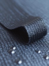 Close-up of a shiny black ribbon on a textured surface with beads, AI generated