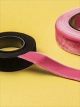 Black and pink fabric ribbons rolled out on a yellow background, AI generated