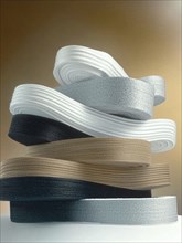 Stack of ribbons in various colors including white, silver, brown, and black, AI generated